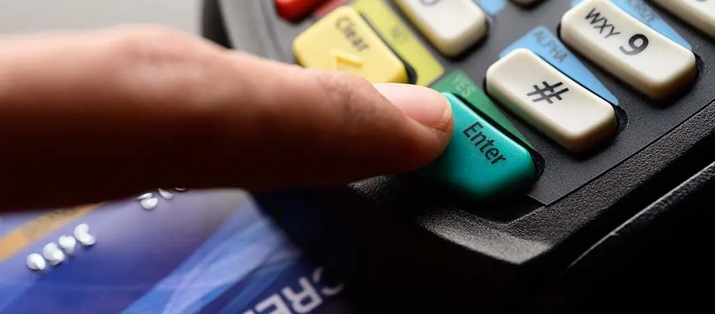 Ujj megnyomja az "Enter" gombot egy bankkártya terminálon, alatta bankkártyák láthatók.