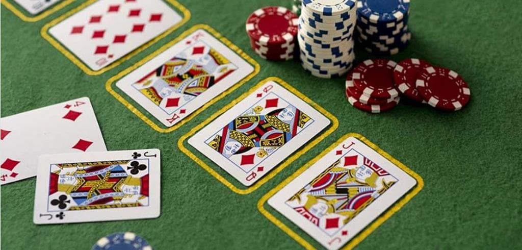 Pókerasztal leosztott lapokkal és kaszinózsetonokkal, Texas Hold’em játék zöld posztón.