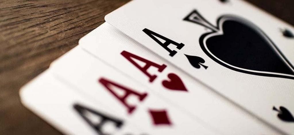 Négy ász kártyalap faasztalon, klasszikus kaszinó játékokhoz, mint a póker vagy baccarat.