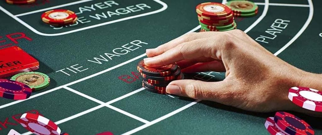 Baccarat asztal zsetonokkal, játékos fogadása a BANKER mezőre.