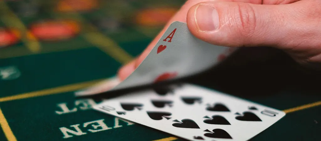 Blackjack kéz közelről, ász és tízes kaszinókártya zöld asztalon, nyerő kombinációban.