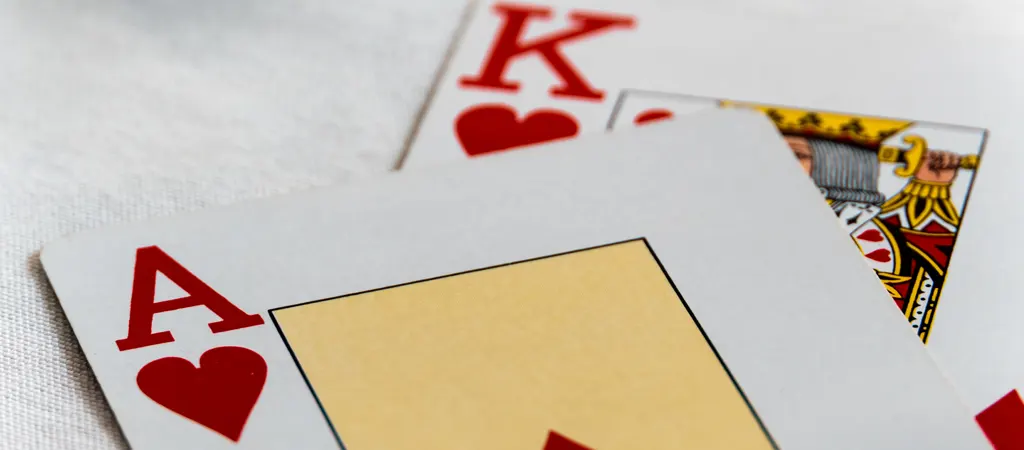 Blackjack kombináció közelről, kőr ász és király kártyalap fehér háttéren.
