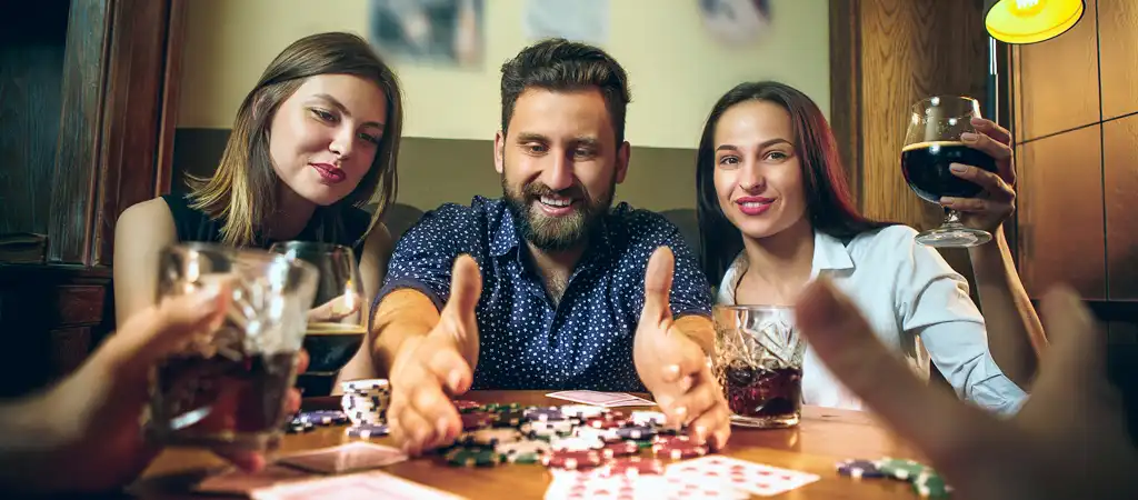 Baráti társaság pókerpartin blöfföl, zsetonok és italok az izgalmas játék pillanataiban.