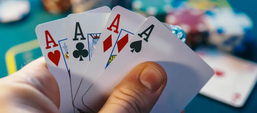 Poker játékos kezében négy ász lap, izgalmas póker pillanat kaszinóban.