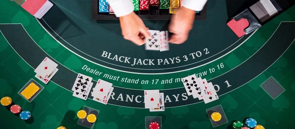 Blackjack játékosok és osztó kártyákkal egy zöld kaszinóasztalon, izgalmas élő kaszinó élmény.