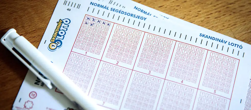 Skandináv lottó szelvény kitöltött részletekkel és tollal, faasztalon elhelyezve, játék logóval.